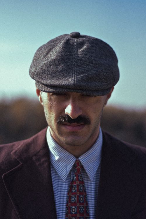 Free Portrait of a man in retro attire with a flat cap and mustache outdoors. Stock Photo