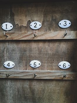 Close-up of numbered hooks on a rustic wooden wall, ideal for vintage decor themes.