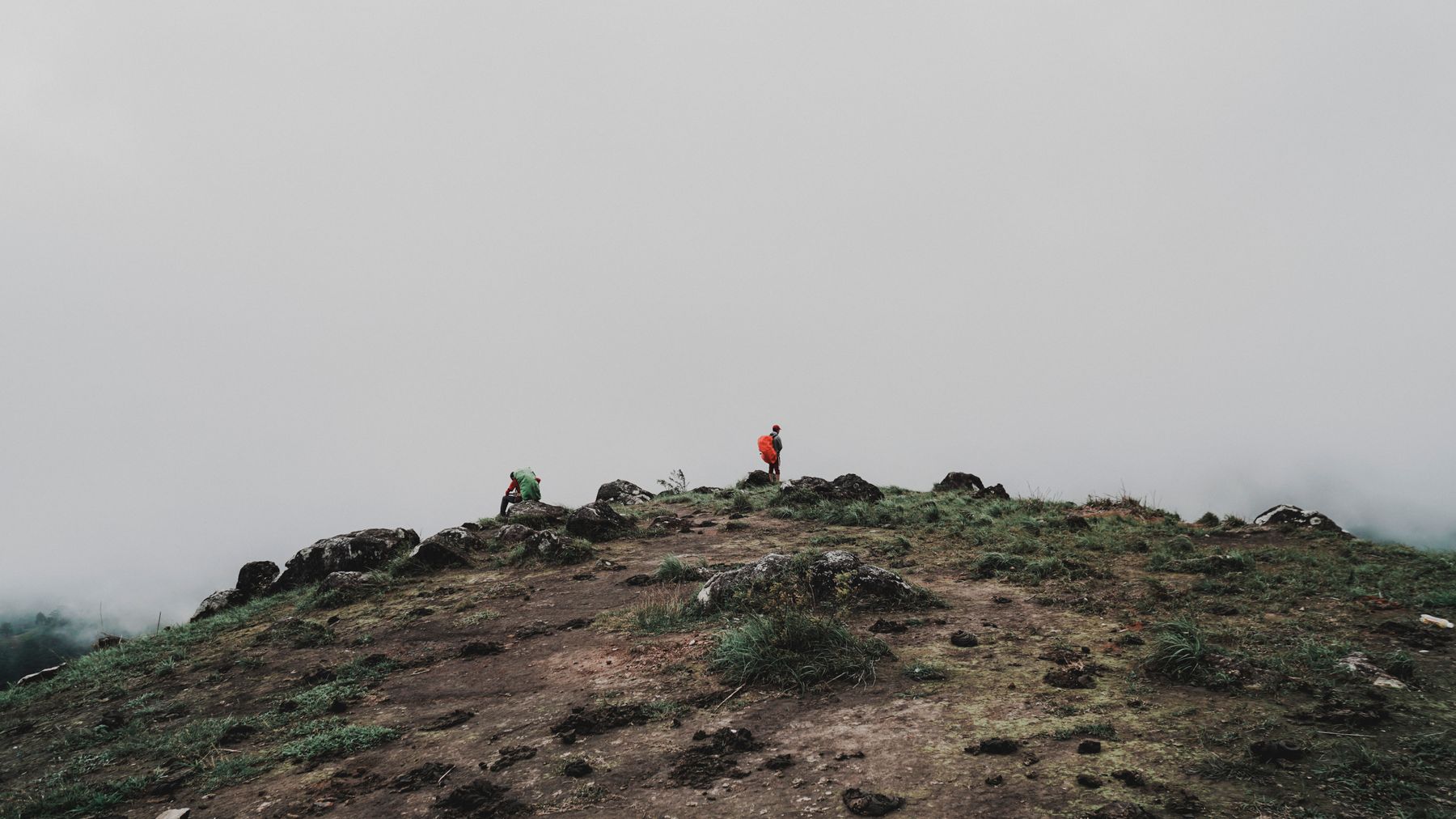 Two hikers on a misty mountain peak, showcasing adventure and exploration.