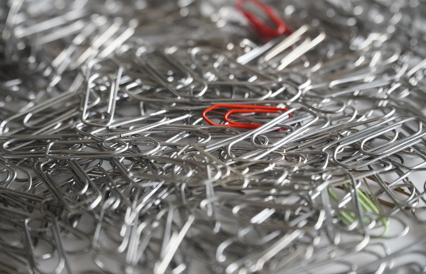 A vibrant mix of red, green, and silver paperclips in a large pile, close-up view.