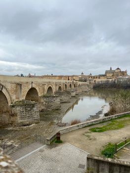 Capture of Córdoba's Roman Bridge and Old Town on a cloudy day, showcasing historical architecture.
