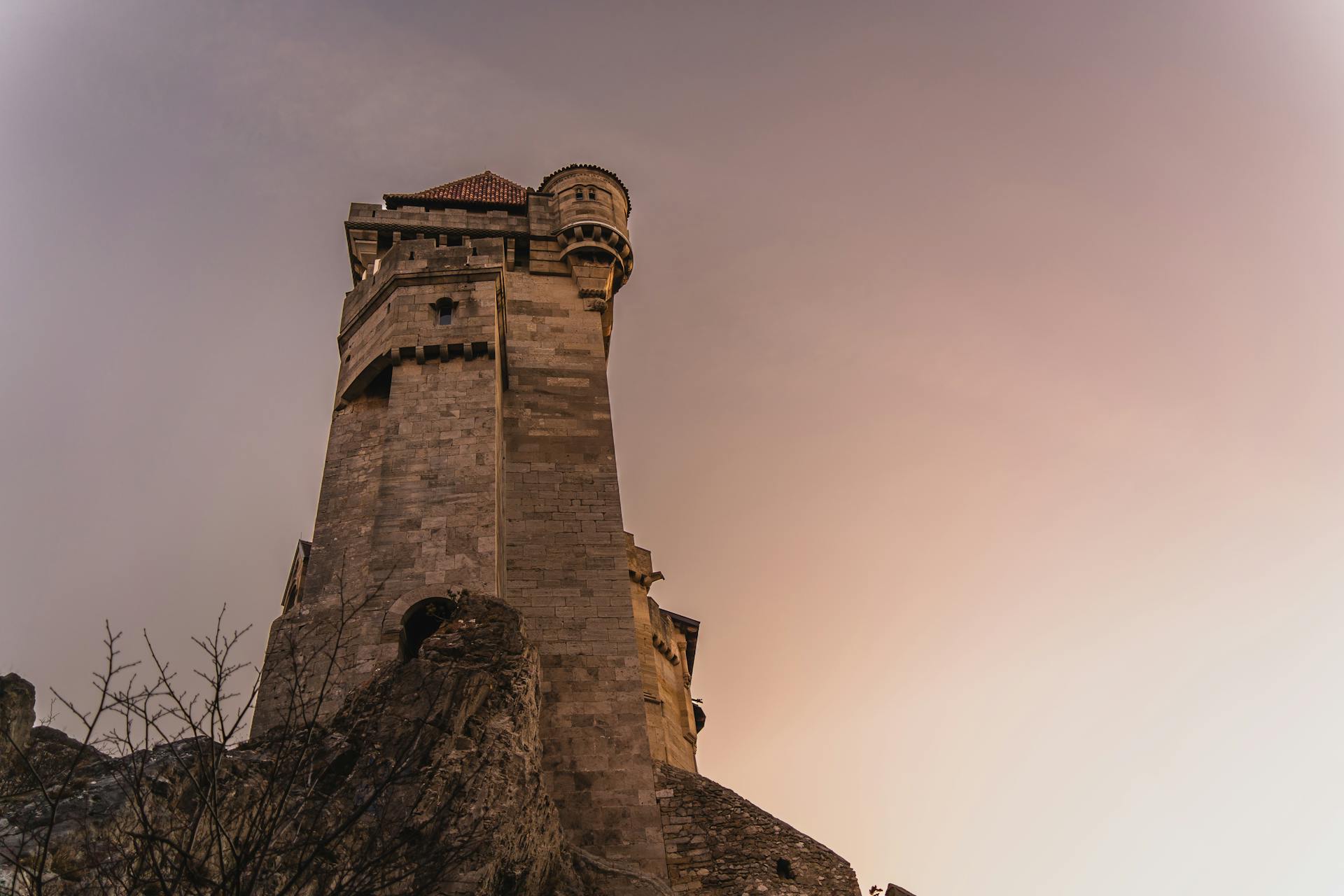 Low angle view of Liechtenstein Castle at dusk, showcasing its historical architecture against a warm sky.