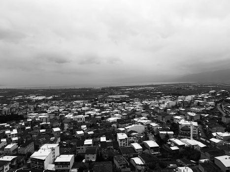 Aerial view of a densely packed city under a cloudy sky, in monochrome. Perfect for urban and architectural themes.