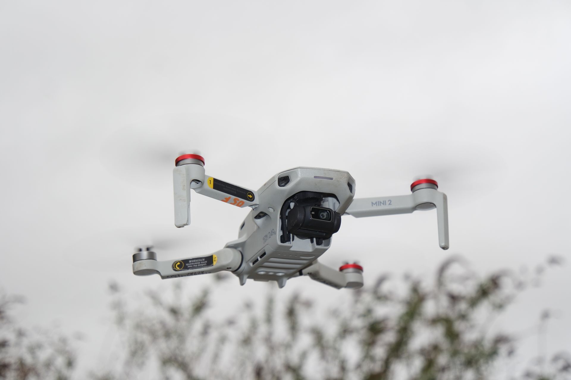 Close-up of a modern drone flying outdoors, showcasing advanced technology and propellers in an overcast sky.
