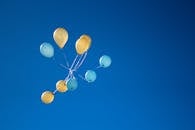 色彩缤纷的黄色和蓝色气球漂浮在清澈的蓝天上，象征着欢乐与庆祝