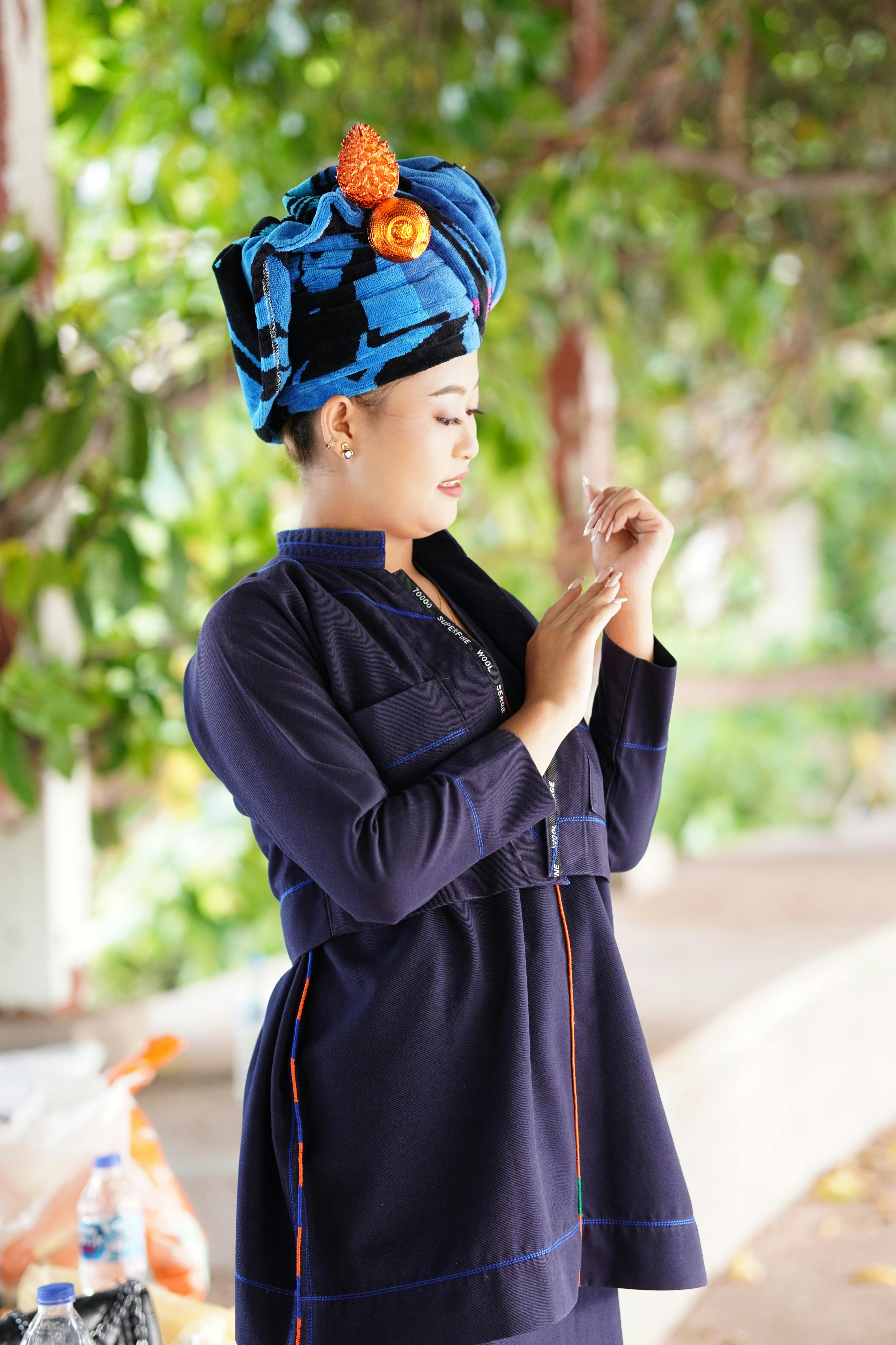 Portrait of an Asian woman in traditional dress and turban, posing thoughtfully outdoors.