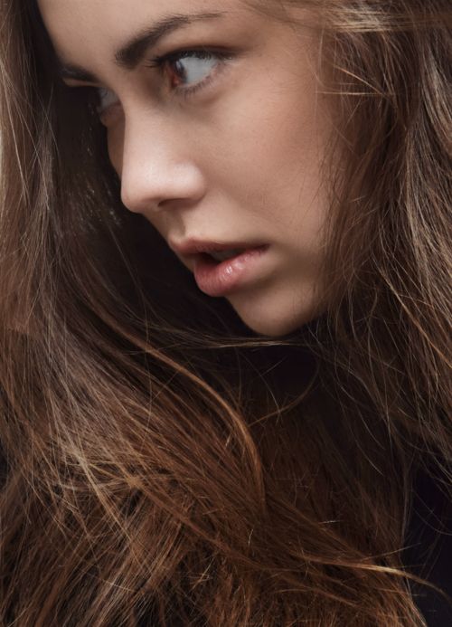 Free Close-up portrait of a young woman with long hair, showcasing emotion. Stock Photo