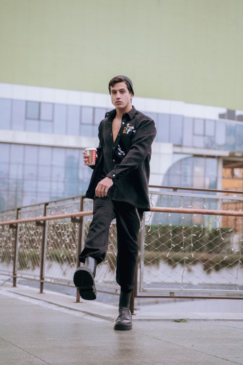 Free A stylish young man walks on a pavement in İstanbul, holding a coffee cup. Stock Photo