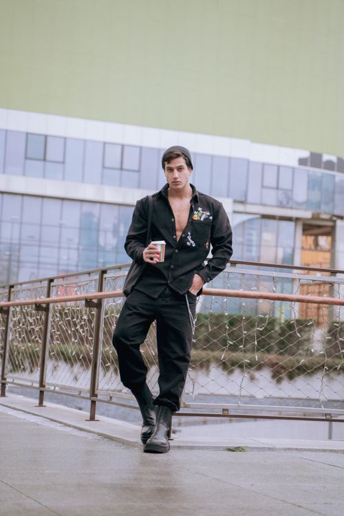 Free Stylish man in black outfit holding coffee, posing in Istanbul's urban setting. Stock Photo