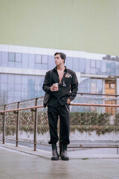 Free Stylish man in black attire holding a cup standing on a modern walkway in Istanbul. Stock Photo