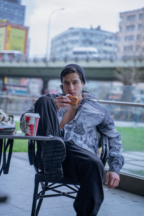 Man Eating a Sandwich on a Balcony 