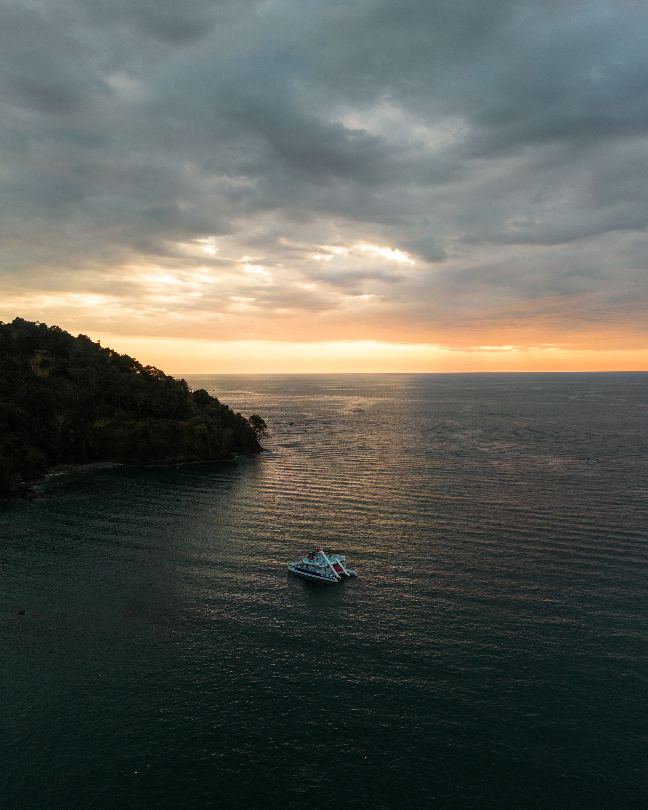 Sunset over calm waters behind a luxury yacht