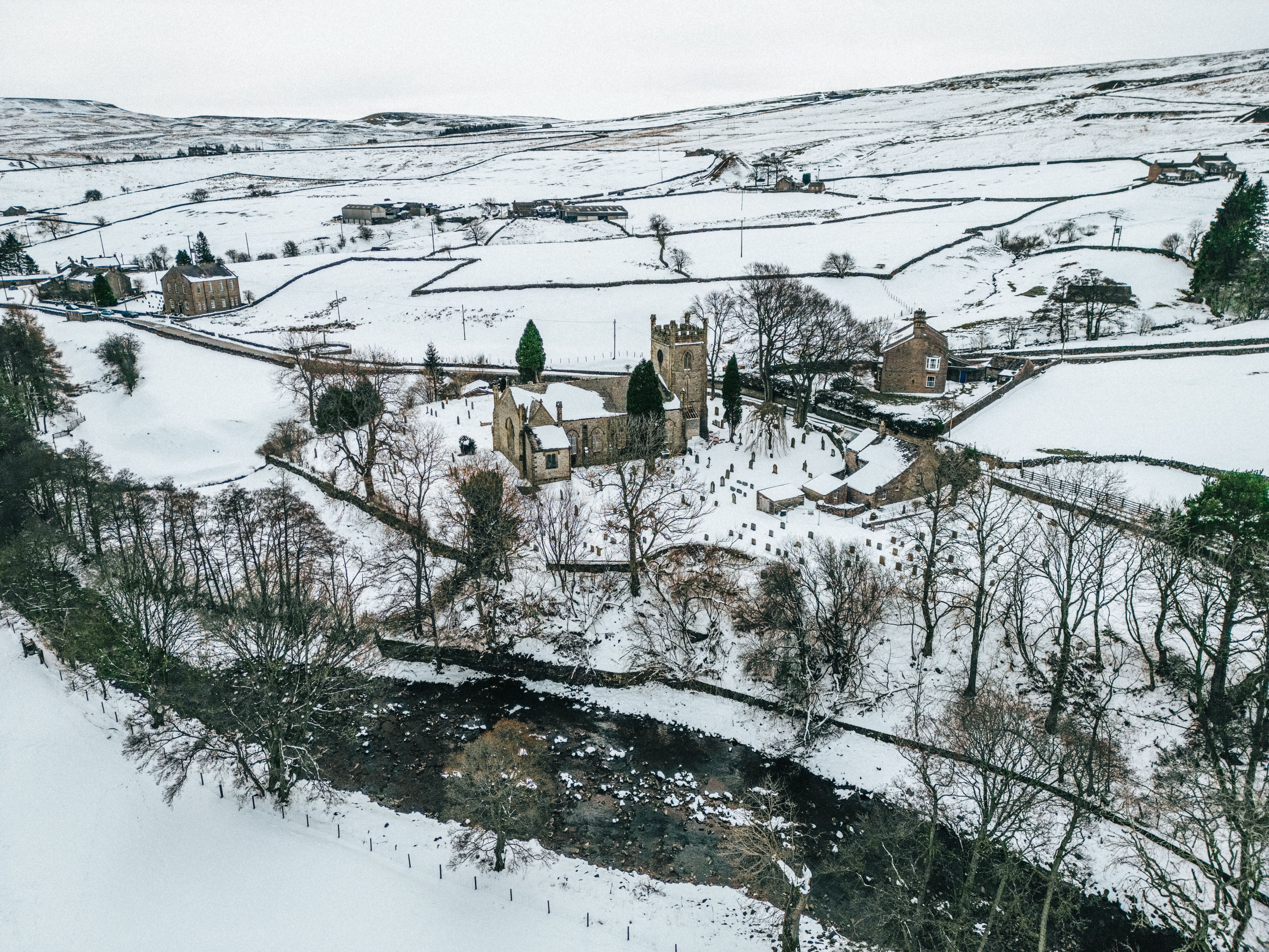 Aerial view of a snow-blanketed landscape featuring a church and river.