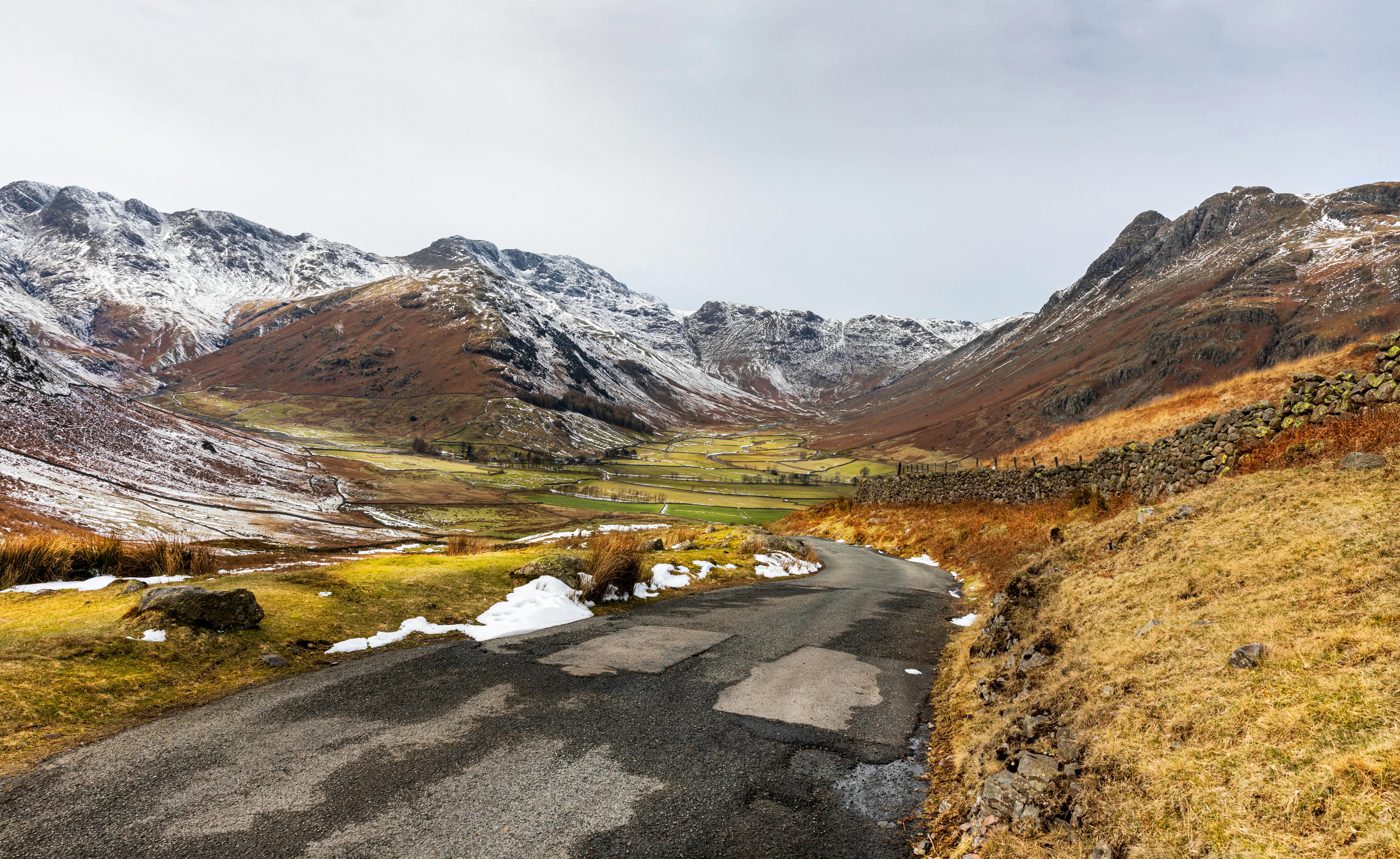Breathtaking view of a road leading through snow-dusted mountains in Little Langdale, UK.