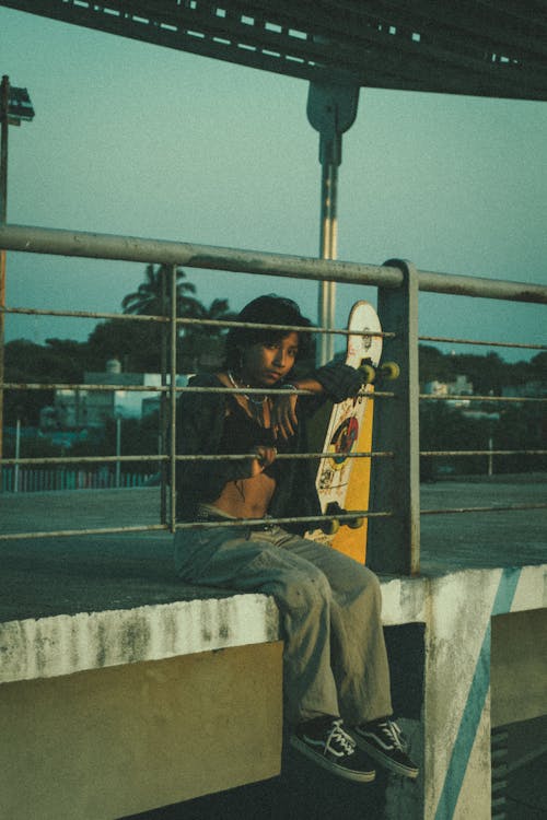 Young Woman Sitting in a Skatepark with Her Skateboard