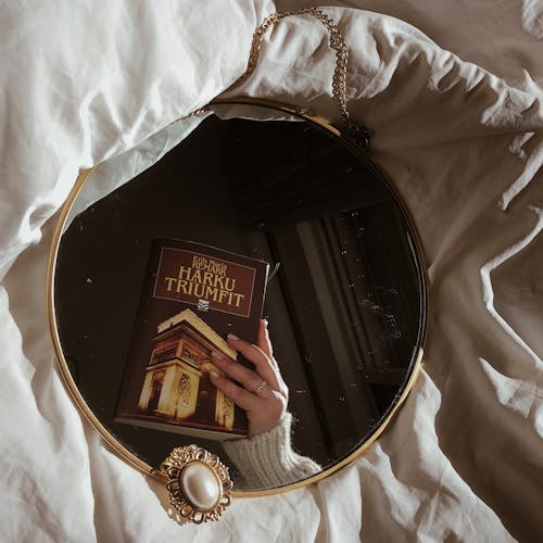 Woman Hand Holding Book Reflection in Mirror