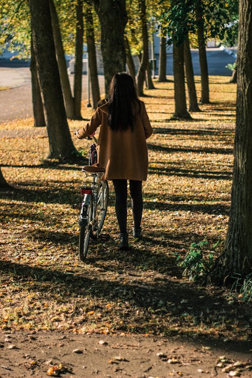 Woman Holding Bicycle Near Trees