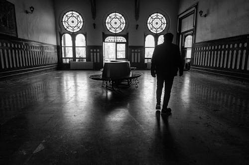 Man Walking in Empty Hall in Black and White