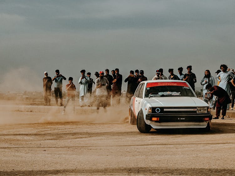 People Watching A Toyota Corolla E70 Drifting On A Desert