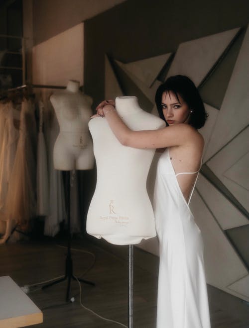 Woman in a White Dress Hugging a Mannequin 