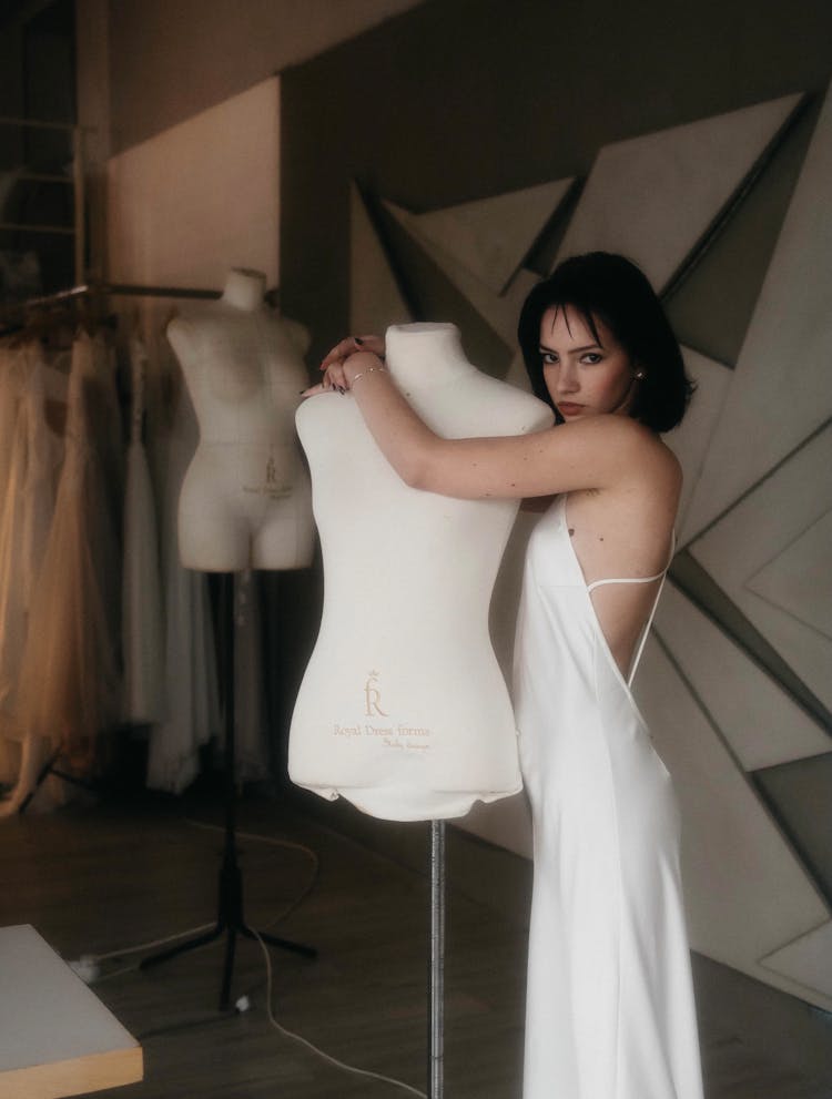 Woman In A White Dress Hugging A Mannequin 