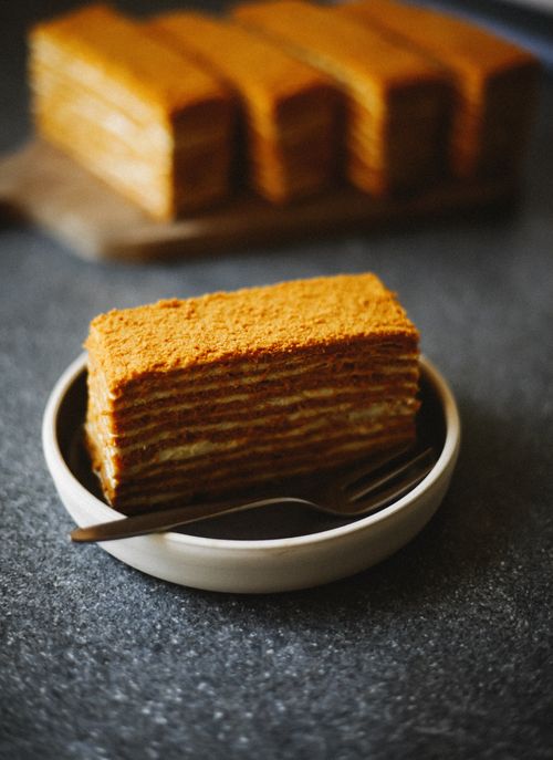 Free Delicious layered honey cake slice on a plate with a fork, perfect for dessert lovers. Stock Photo