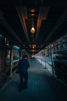 A lone man walking under city scaffolding at night in Chicago.