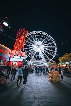 Vibrant night scene at Toronto's amusement park with a bright Ferris wheel and crowds enjoying the festivities.