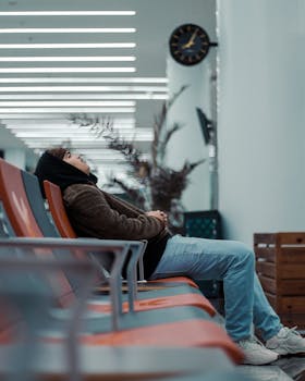 A man wearing a hooded jacket sits in a modern airport lounge in Rabat, Morocco.