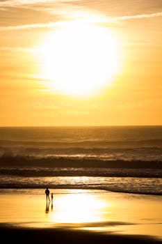 A parent and child enjoy a peaceful walk on a Sintra beach at sunset.