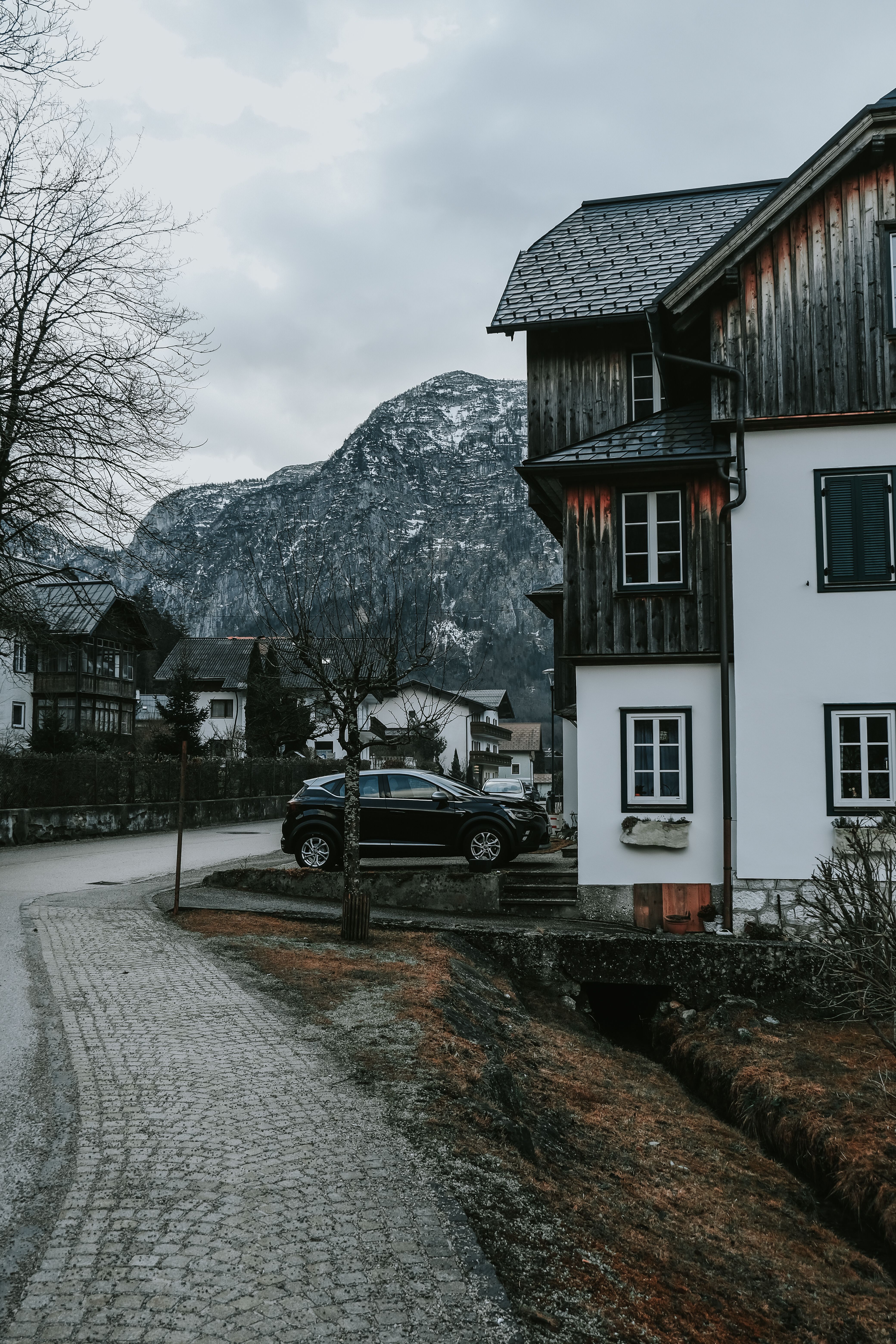 A car parked in front of a house on a mountain road · Free Stock Photo