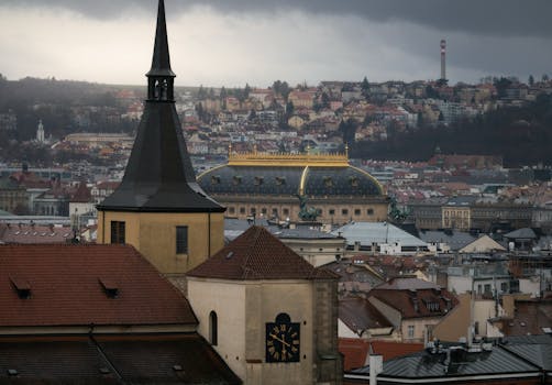 A moody view of Prague's skyline featuring historic architecture and a cloudy sky.