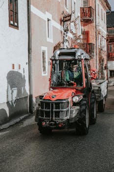 Tractor on a quaint village street with European architecture, evoking a rustic charm.