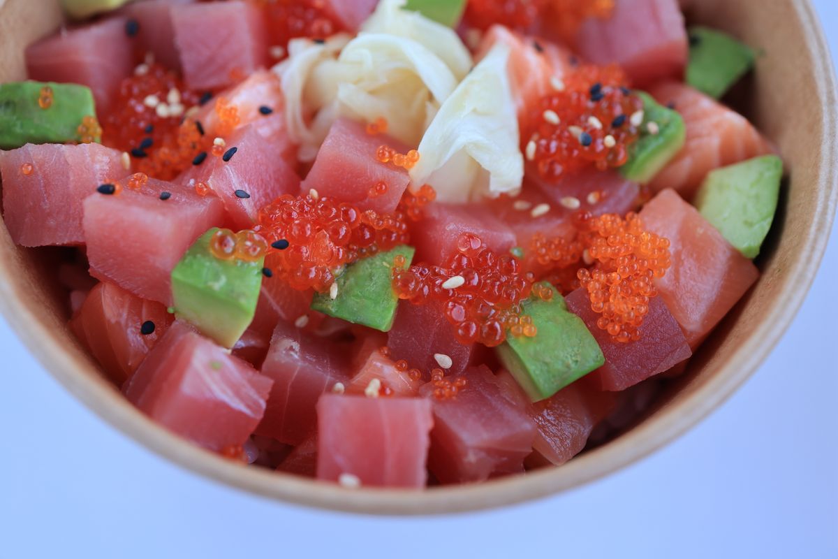 Close-up of cubed raw tuna with avocado, orange tobiko, sesame seeds and pickled ginger