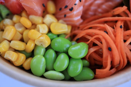 A vibrant close-up of salmon poke bowl with corn, edamame, and carrots.