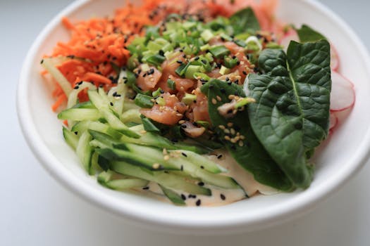 A vibrant salad bowl with salmon, spinach, cucumber, and carrots, perfect for a healthy meal.