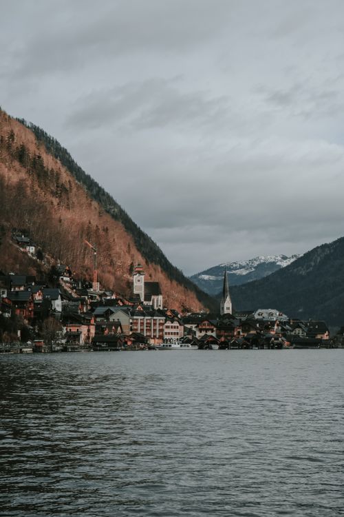 Free Charming village by a tranquil lake surrounded by mountains, ideal for travel enthusiasts. Stock Photo