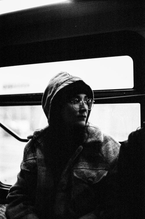 Free A woman wearing a hat and glasses sits on a bus in a black and white photo. Stock Photo
