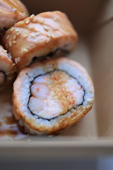 Delicious sushi roll with salmon and sesame seeds, drizzled with soy sauce, in a close-up shot.