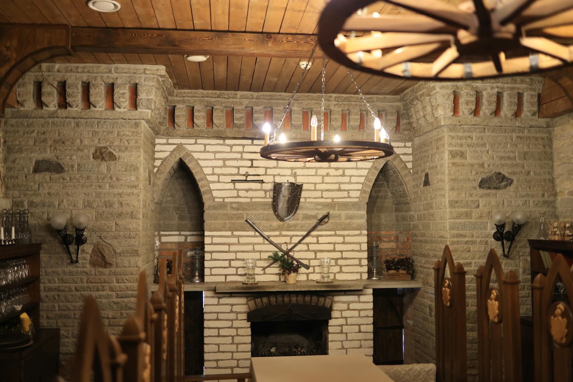 A medieval-themed basement interior with stone walls, wooden decor, and a fireplace.