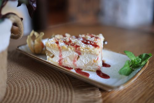 Free Close-up of a creamy cake slice drizzled with berry sauce, garnished with mint. Stock Photo