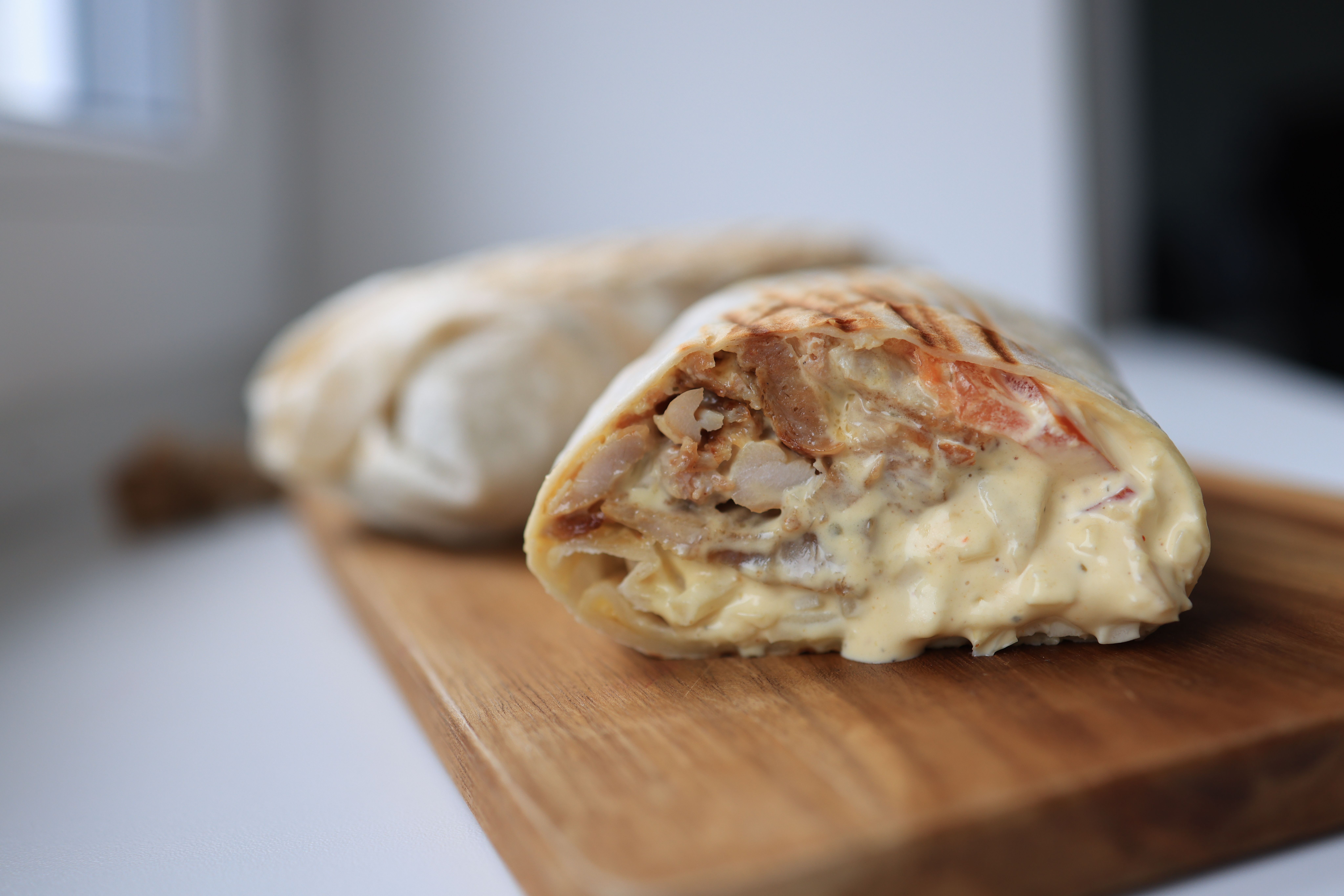 Free Tasty chicken wrap filled with creamy sauce on a wooden cutting board. Stock Photo