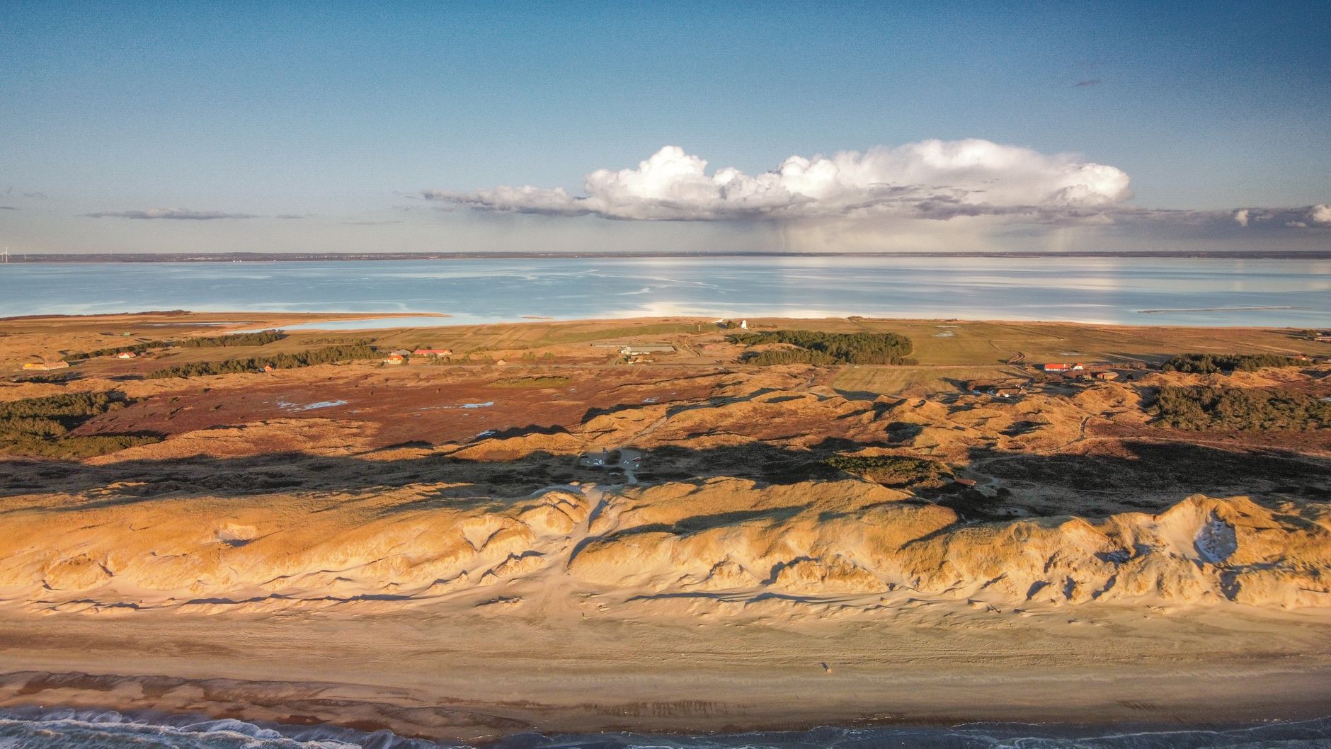 Drone capture of Hvide Sande's scenic coastline with sandy beaches and sunlit landscape.