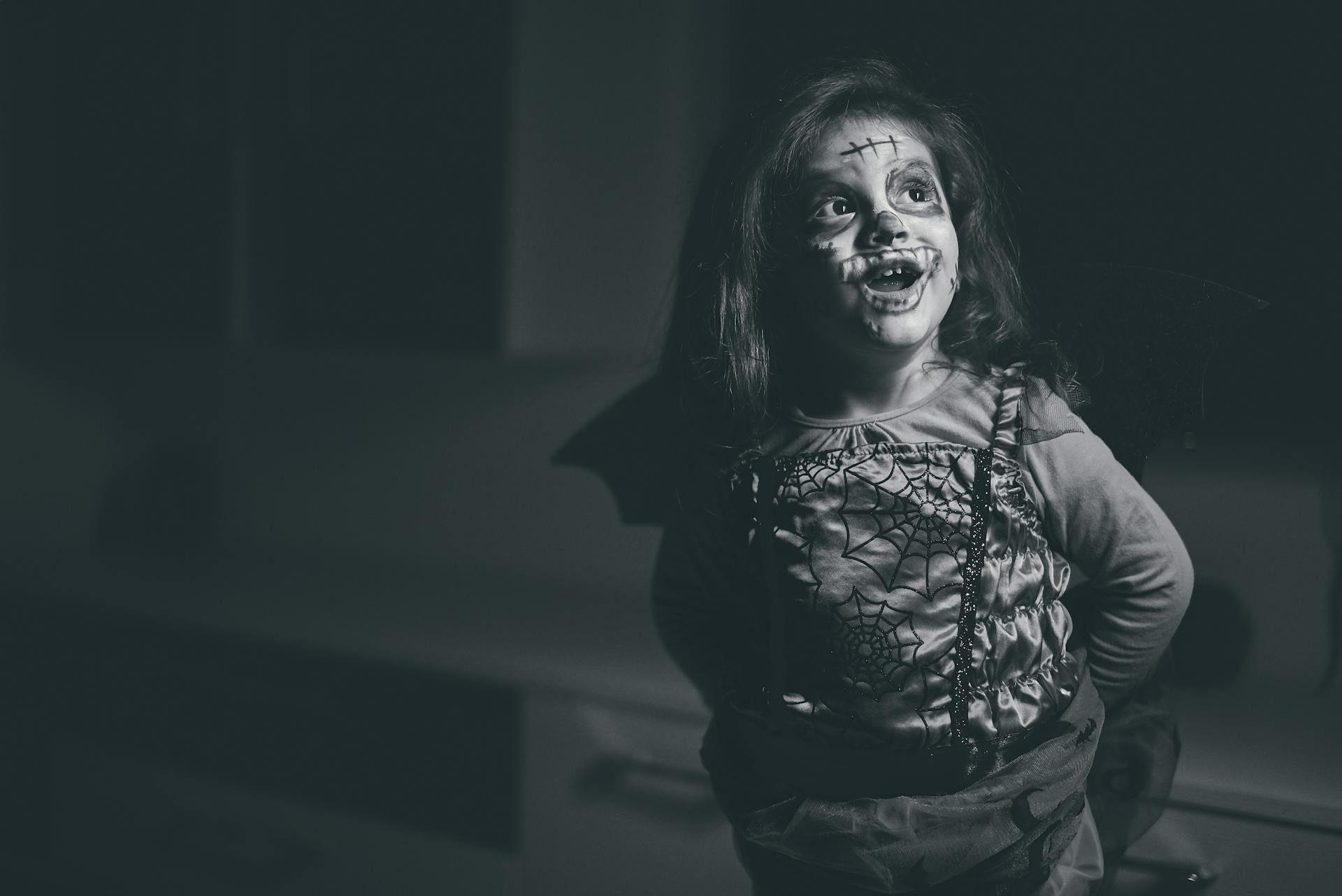 Grayscale Photo of Smiling Girl In Halloween Costume