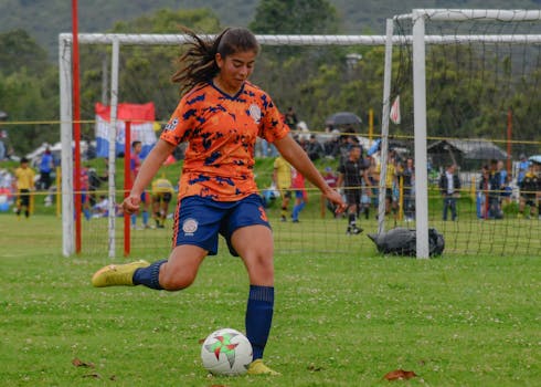 A female soccer player in action on a grassy field, showcasing skill and concentration.