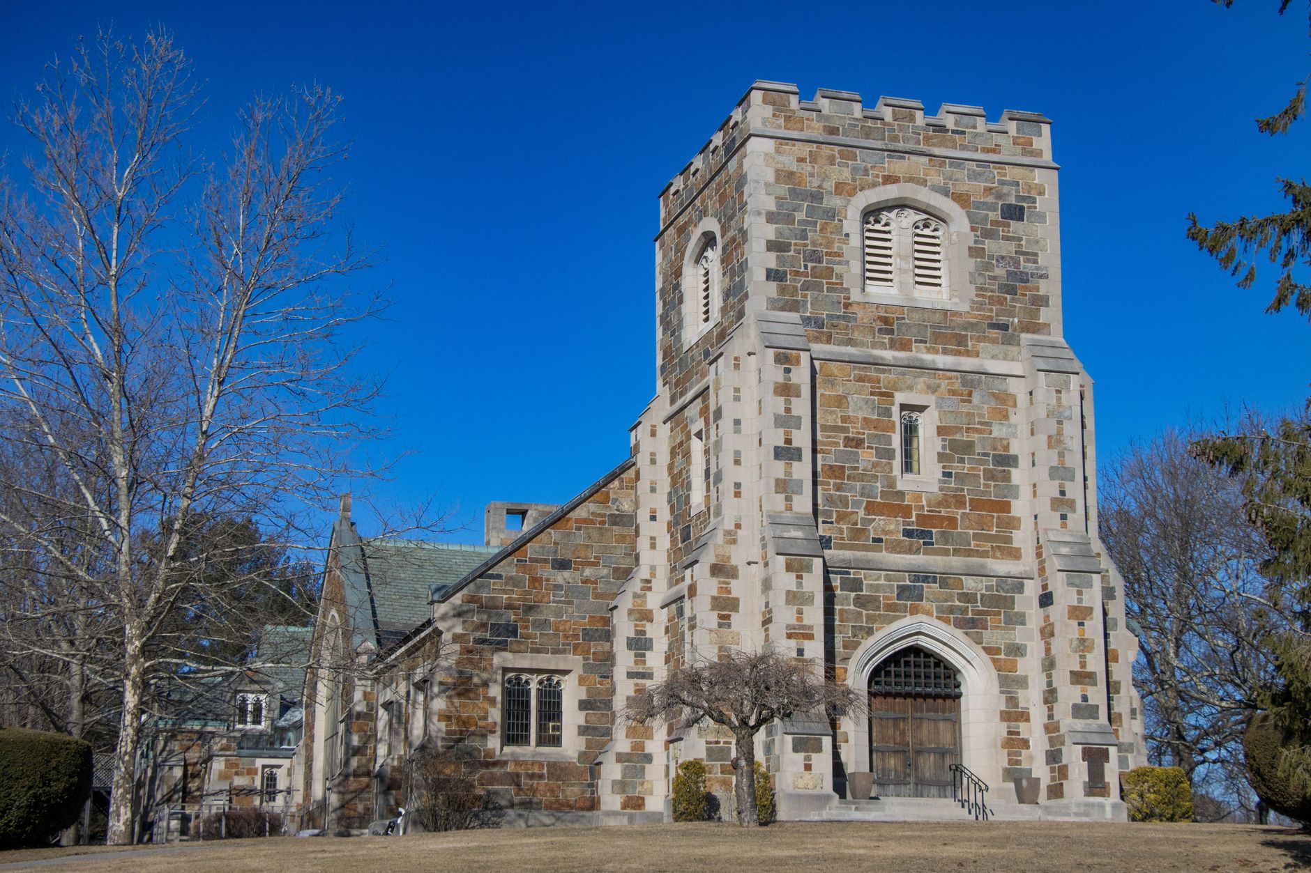 Medieval-style stone church tower with blue sky in Newton, Massachusetts.