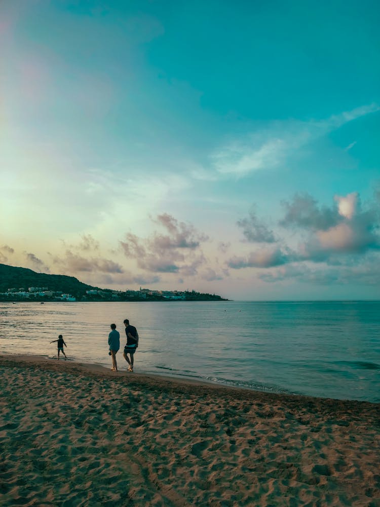 Couple Walking With Child On Beach