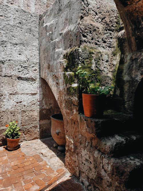 Free A charming courtyard with weathered stone walls and potted plants, creating a rustic ambiance. Stock Photo