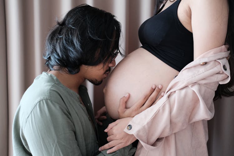 Man Kissing Stomach Of Pregnant Woman