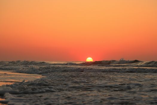 A stunning sunrise over the Atlantic Ocean at Hilton Head Island, SC, with gentle waves reflecting warm colors.